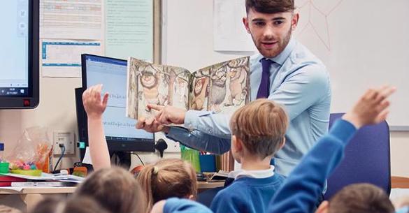 Primary school teacher reading 'Where the wild things are' to group of children